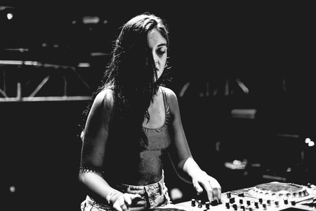 Young woman Dj playing music at Summer Night Festival. Fun, youth, entertainment and fest concept.の写真素材