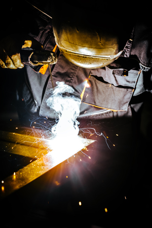 Professional mask protected welder man working on metal welding. Selective Focus.