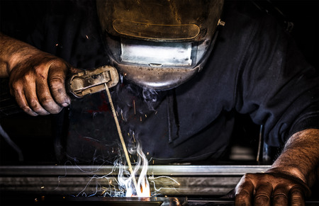 Professional mask protected welder man working on metal welding and sparks metal.の写真素材