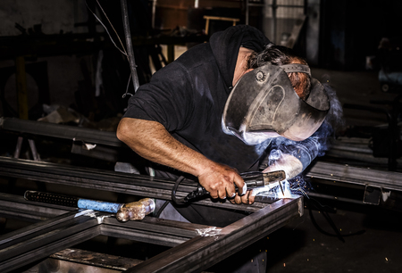 Professional mask protected welder man working on metal welding