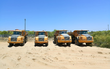 Dump trucks parked in the sand ready for maintenance work on the beach.の写真素材