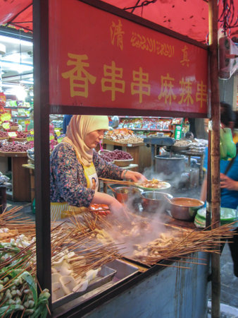 Xian, China - July 09, 2010: Muslim Chinese from Hui ethnic cooking stacks of meat skewers on Beiyuanmen Moslem Street, Muslim Quarters, Xian China.のeditorial素材