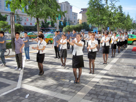 Xian, China - July 10, 2010: Uniformed Chinese workers exercising in the street at morning. Employees exercising collectively at the boss's orders is an important part of the landscape of work in contemporary China.のeditorial素材