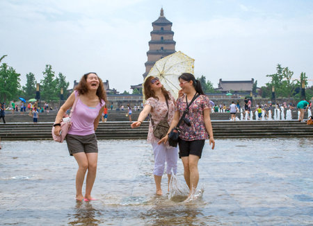 Xian, China - July 25, 2010: Local people playing with the water during summer in the Music Fountain, Dayan Pagoda Square, Xian, China. For most tourists, the square is famous for its big music fountain, which is said to be the largest music fountain in Aのeditorial素材