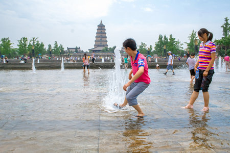 Xian, China - July 25, 2010: Local people playing with the water during summer in the Music Fountain, Dayan Pagoda Square, Xian, China. For most tourists, the square is famous for its big music fountain, which is said to be the largest music fountain in Aのeditorial素材