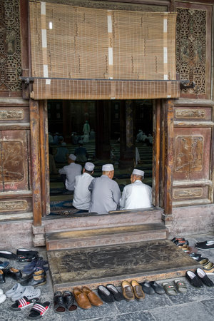 Xian, China - July 12, 2010: Old Muslim chinese men praying at the Xian Great Mosque in the city of Xian. The Great Mosque, located in the center of the city, is the largest and one of the most important Islamic places of worship in China. The Great Mosquのeditorial素材