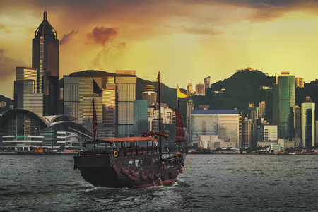 Traditional wooden sailboat sailing in victoria harbor at sunset in Hong Kong, China.の写真素材