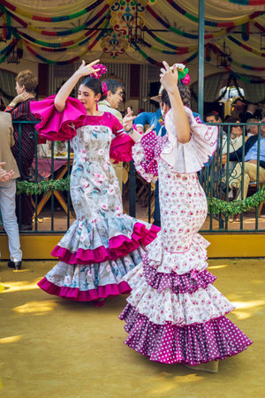 Sevilla, Spain - April 18, 2018: Young women wearing flamenco dresses and dancing "Sevillanas" at the April Fair, Seville Fair (Feria de Sevilla). The Seville Fair (officially and in Spanish: Feria de abril de Sevilla, "Seville April Fair") is held in Andのeditorial素材