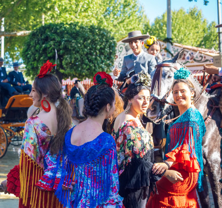 Sevilla, Spain - April 18, 2018: Beautiful women in traditional and colorful dress enjoy April Fair, Seville Fair (Feria de Sevilla). The Seville Fair (officially and in Spanish: Feria de abril de Sevilla, "Seville April Fair") is held in Andalusian capitのeditorial素材