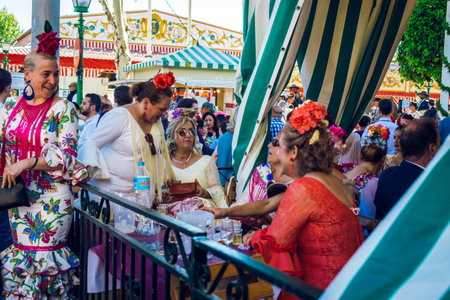 Sevilla, Spain - April 18, 2018: Women dressed in traditional costumes enjoy April Fair , Seville Fair (Feria de Sevilla). The Seville Fair (officially and in Spanish: Feria de abril de Sevilla, "Seville April Fair") is held in Andalusian capital of Sevilのeditorial素材