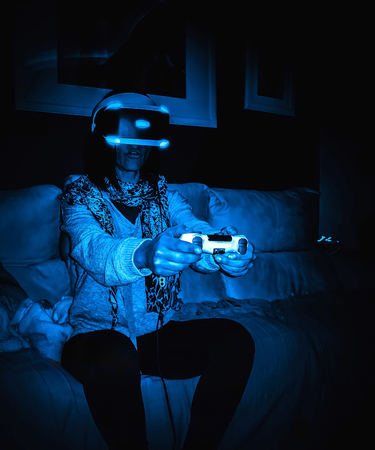 Woman with virtual reality headset sitting on the couch at home.の写真素材