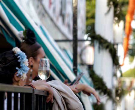 Hand holding glass of fino sherry (manzanilla sherry) at the April Fair (Feria de Abril), Seville Fair (Feria de Sevilla), Andalusia, Spain. Travel and tourism concepts. Selective focus.の写真素材