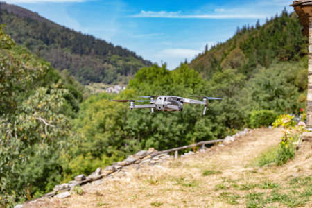Quadcopter drone with digital camera in flight with landscape and blue sky background.の写真素材