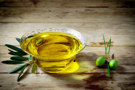 Olive oil and olive branch on the wooden tableの写真素材