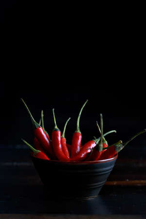 Red hot chili peppers bowl on wooden table and black background ..