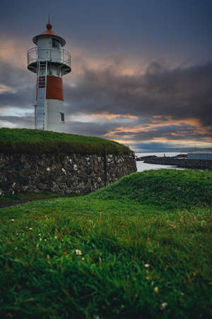 Old lighthouse against incredible sunset sky in Old Town of Torshavn, capital of the Faroe Islands,...