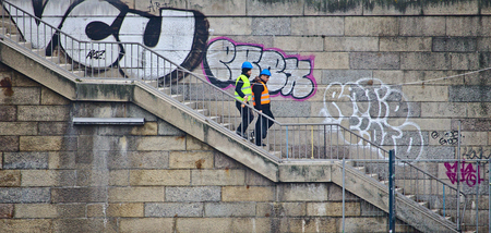 Bremen, Germany - March 8th, 2017 - Two construction workers wearing hi-viz vests and helmets...
