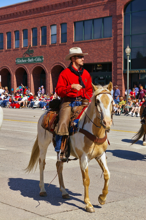 Cody, Wyoming, USA - Cowboy with bright red shirt riding on the Independence Day Paradeのeditorial素材