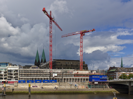 Bremen, Germany - July 10th, 2018 - Construction site of the new Kuehne building on the bank of the river Weser with huge cranes and church spires in the distanceのeditorial素材