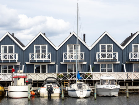 Blue and white terraced houses at a harbor next to the water with yachts in the foregroundの写真素材