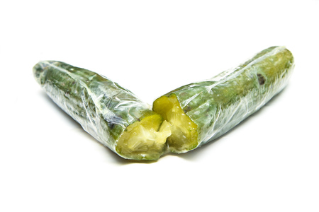 A picture of a rotten cucumber packed in the plastic foil. The foil is useless, it only damages the vegetable and it only goes mouldy. Isolated on a white background.の写真素材