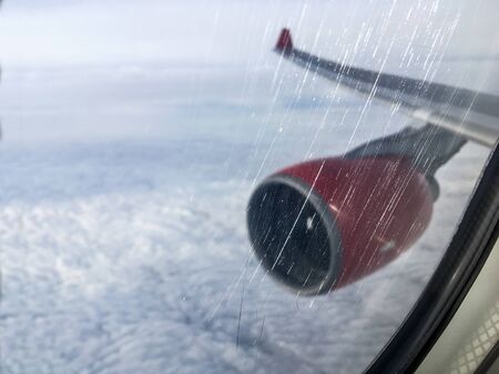 An aerial view from the airplane flying high above the ground. A look from the planeÂ´s window with engine and wing visible. Focused on the scratchesの写真素材