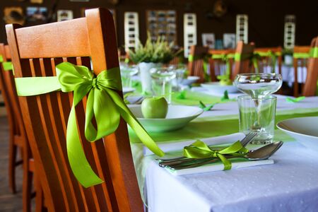 A detail picture of the table prepared for wedding lunch. All  accessory is in green color. The fresh green apple is on the plate.の写真素材