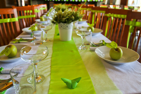 A detail picture of the table prepared for wedding lunch. All  accessory is in green color. The fresh green apple is on the plate.の写真素材