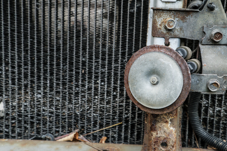 A detail of the old car wreck. The dirty radiator full of mess with a stone inside and the rusty horn are visible.の写真素材