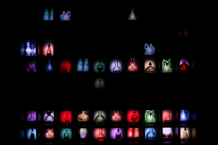 A picture of the black wall with small vintage glass bottles with a colorful liquids inside. Looks...