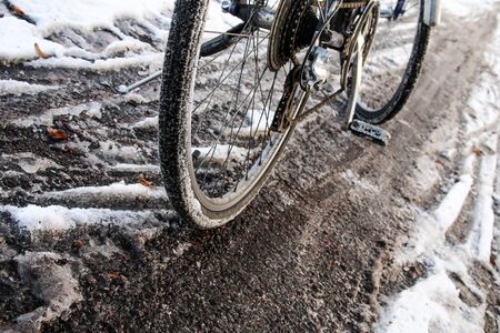 A detail of the bicycle on the dirty cycleway during winter. Only narrow track is visible and can be used.の写真素材