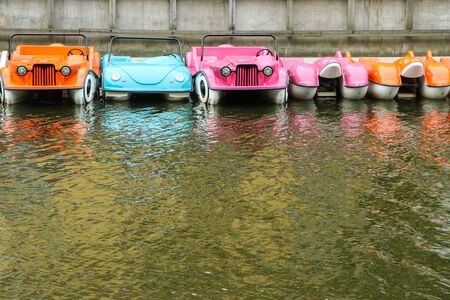 Several colorful paddle boats floating on the water by the riverbank and waiting for the tourists.の写真素材