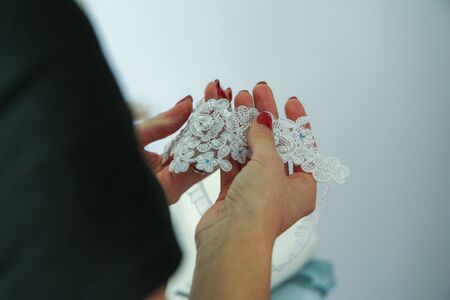 A woman is holding the wedding garter belt in her hands. A detail from the ceremony preparations.の写真素材