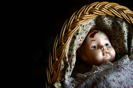 The unused old doll with a hole in its head is lying in the baby carriage and looking quite scary and depressive.の写真素材