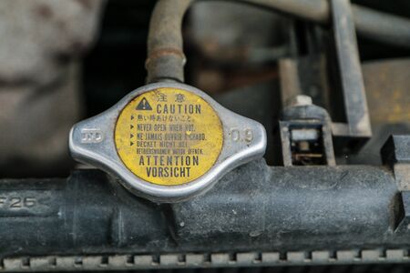 A detail of the old car wreck. The pressure cap of the radiator with a warning can be seen.の写真素材