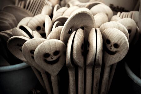 A detail picture of the wooden cooking spoons with carved faces. They are smiling, but also look a bit scary, like some ghosts.の写真素材