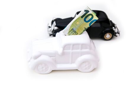 The ceramic car shaped money box with a banknote inside with model car behind. It can be symbol for costs for carÂ´s repairs, investment, savingsの写真素材