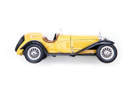 The yellow toy model of the old retro car. Isolated on a white background.