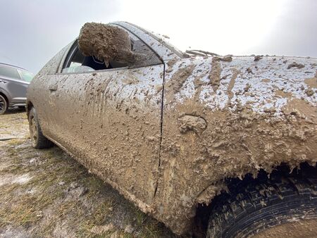The detail of the car completely dirty by mud after the drag race on a field during winter. It needs...