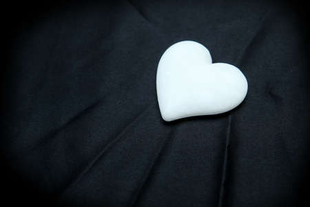 The white marble stone heart lying on the black satin. Romantic background, symbol for love.の写真素材