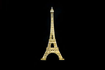 The small golden Eiffel tower as a souvenir from Paris. Isolated on a black background.の写真素材