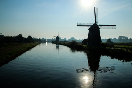 The view from the Dutch countryside by the city of Alkmaar in Netherlands. The canal with the windmills nearby the city.の写真素材