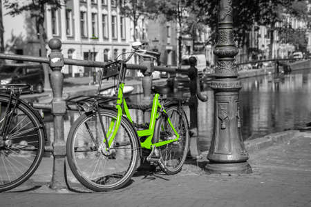 A fresh green bike on the streets of Amsterdam. Symbol for clean and ecological urban transport. Isolated in a black and white background.の写真素材