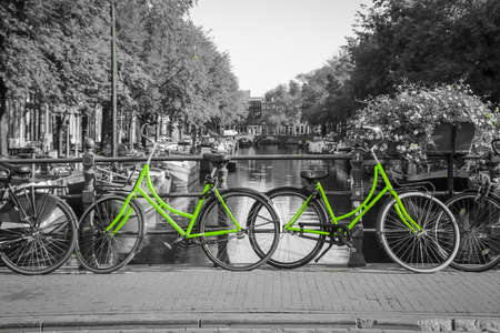 Two fresh green bikes on the streets of Amsterdam. Symbol for clean and ecological urban transport. Isolated in a black and white background.の写真素材