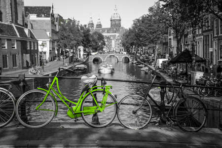 A fresh green bike on the streets of Amsterdam. Symbol for clean and ecological urban transport. Isolated in a black and white background.の写真素材