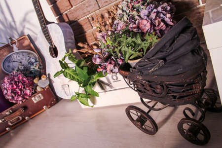 A still life with a small baby carriage, white guitar, basket, box and dry colorful flowers.の写真素材