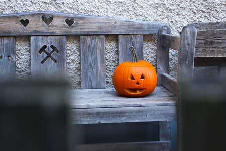 A pumpkin with a carved face on a bench during Halloween.の写真素材