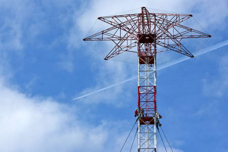 The workers are working high above on an old transmission tower.