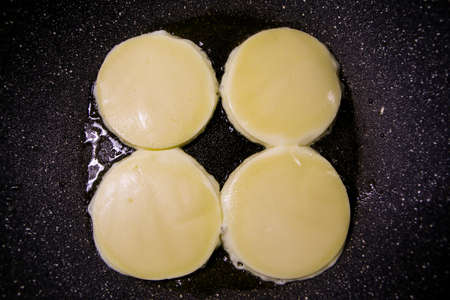 The detail of four cheeses on the non-stick frying pan made of eartenware.