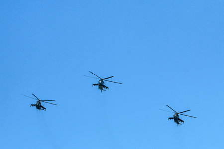 The flight of three soviet battle helicopters, type MIL Mi-24 flying on the bright blue sky.